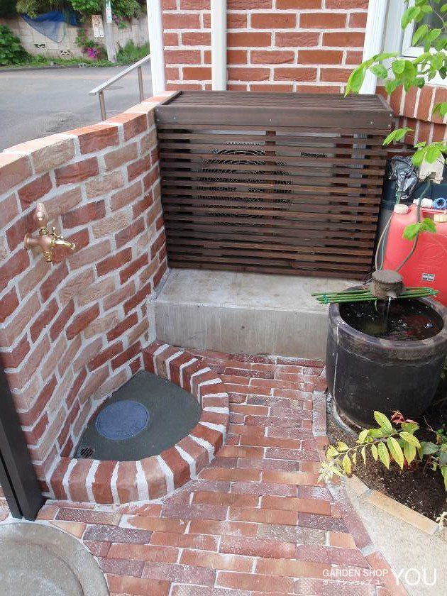 塀を兼ねた立水栓は優しくカーブを描いて。旧いお庭にあった水鉢がさりげないアクセント。
