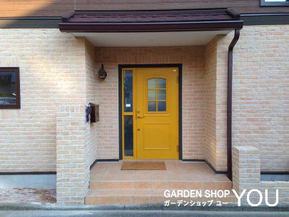 淡いレンガのシンプルな外構ゆえ、パッと目を引く黄色のドア